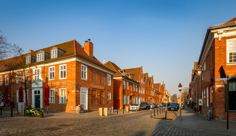 Straße im Holländischen Viertel von Potsdam mit roten Backsteinhäusern, Kopfsteinpflaster, geparkten Autos und historischem Stadtbild.