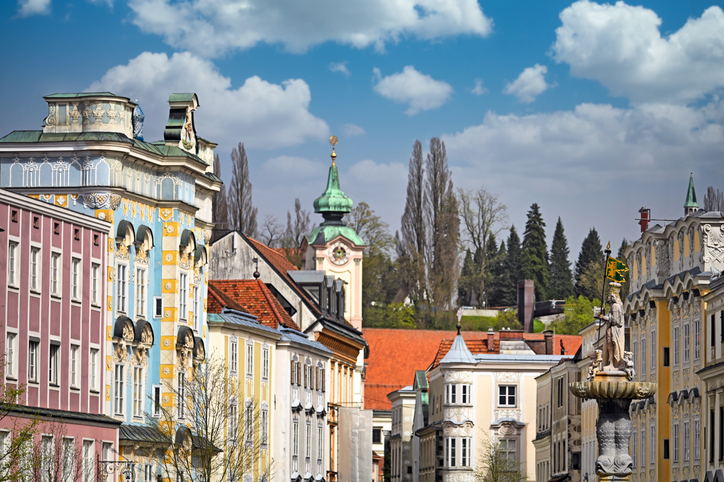 Historische Häuserfassaden und Kirchturm in der Altstadt von Steyr unter blauem Himmel.