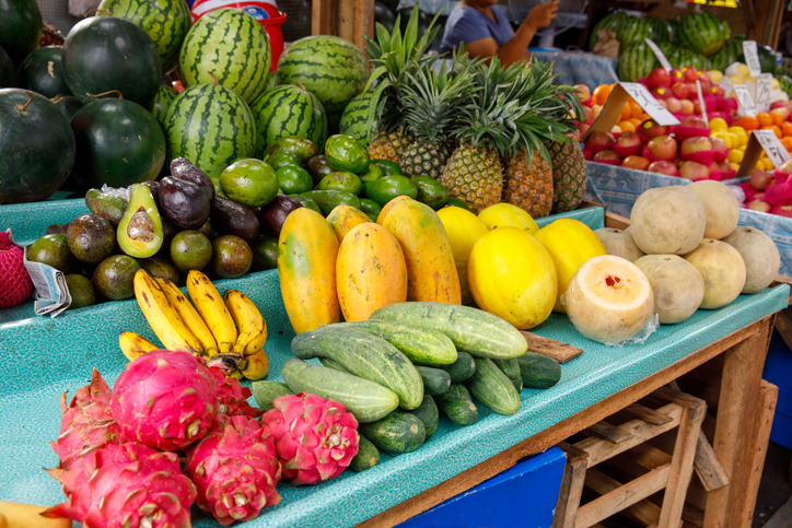 Marktstand mit tropischen Früchten wie Ananas, Melonen, Bananen und Drachenfrucht