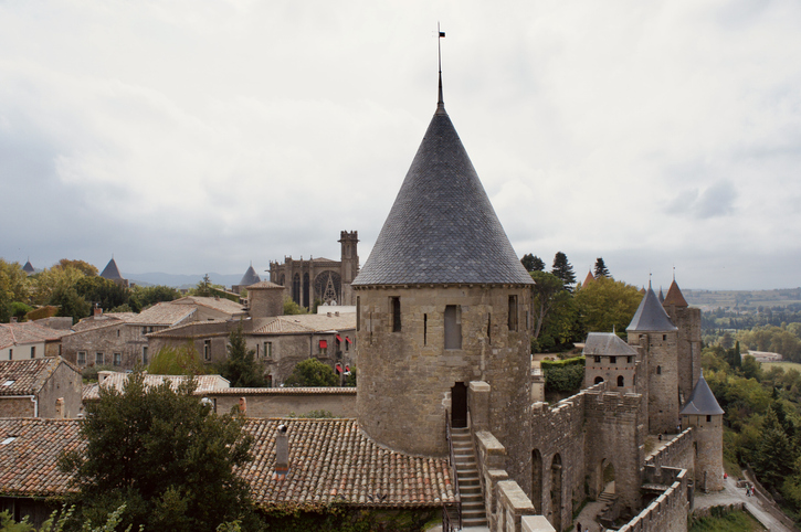 Ein runder Turm und Teile der Stadtmauer von Carcassonne ragen über die Dächer der Altstadt hinaus.