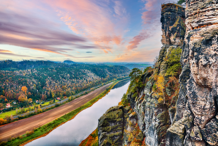 Eindrucksvolle Felslandschaft mit steilen Sandsteinformationen und Flussblick im Umland von Görlitz bei stimmungsvollem Abendhimmel.