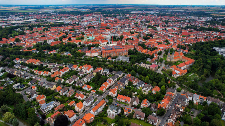 Luftaufnahme von Hildesheim mit dicht bebauter Innenstadt, zahlreichen roten Ziegeldächern, Kirchtürmen, Grünflächen und Wohnvierteln.
