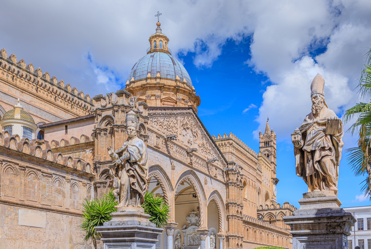 Verzierte Fassade der Kathedrale von Palermo mit Kuppel, Bögen und Statuen unter blauem Himmel