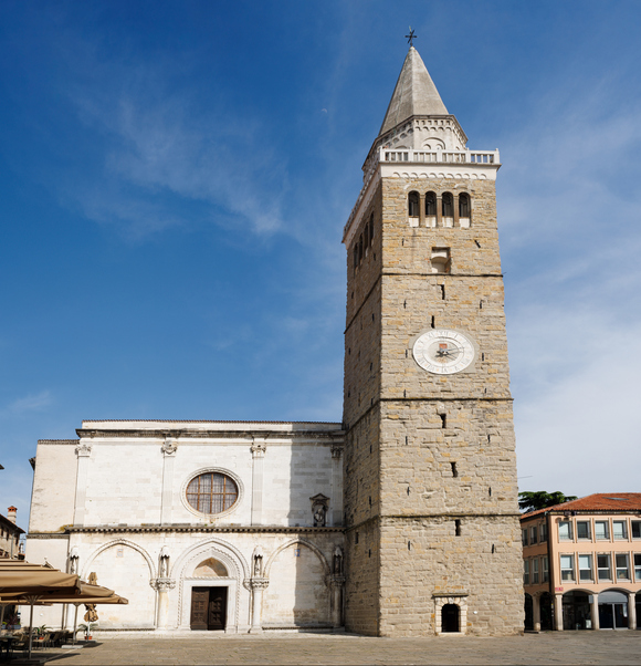 Historische Kirche mit hohem steinernen Glockenturm auf einem Platz in Koper