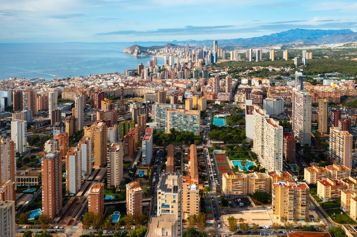 Stadtbild von Benidorm mit vielen Hochhäusern, Wohnanlagen und der Küste im Hintergrund