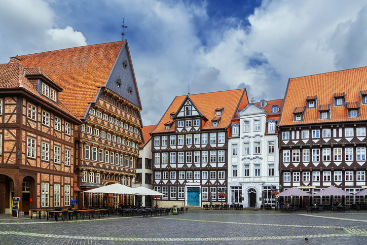 Marktplatz in Hildesheim mit prächtigen Fachwerkhäusern, historischen Fassaden, Kopfsteinpflaster und Straßencafés unter blauem Himmel.