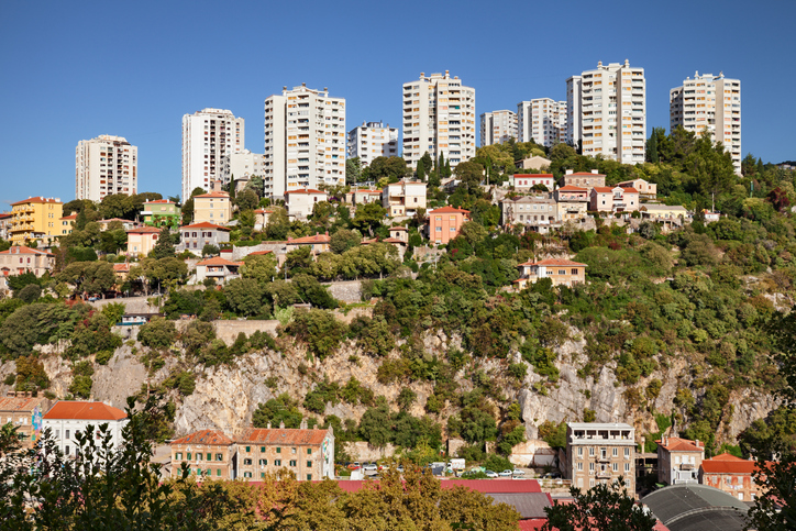 Wohnhäuser und Hochhäuser auf einem grünen Hang über der Stadt Rijeka