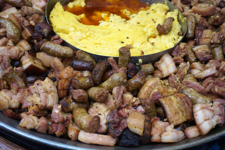 Traditionelles Gericht mit Polenta, Würstchen und gebratenem Fleisch