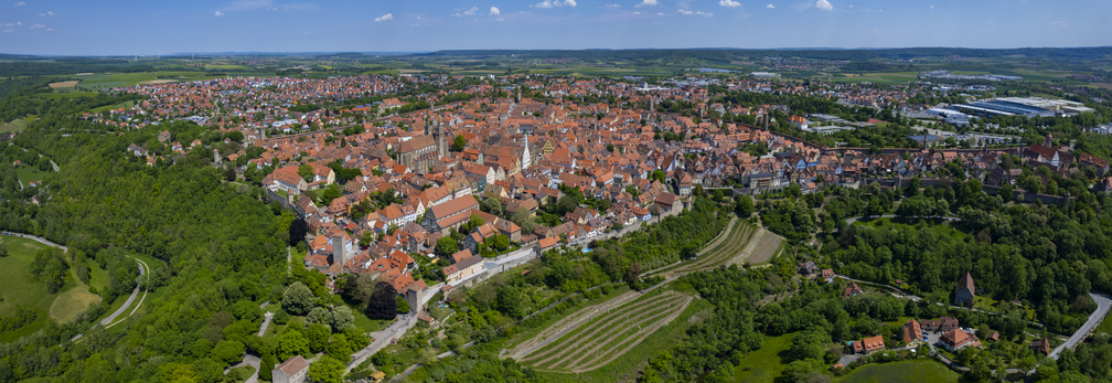 Panorama-Luftaufnahme von Rothenburg ob der Tauber mit kompakter Altstadt, Stadtmauer und grüner Landschaft rundherum.