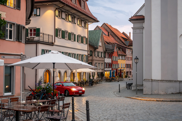 Eine ruhige gepflasterte Gasse mit farbigen Häusern und Außengastronomie führt durch die Altstadt von Meersburg.