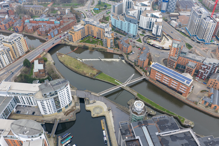 Luftaufnahme von Leeds mit River Aire, modernen Wohn- und Geschäftsgebäuden, Brücken und Wasserwegen im Stadtzentrum.