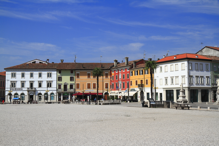 Weitläufiger Hauptplatz von Palmanova mit bunten Bürgerhäusern und Außengastronomie