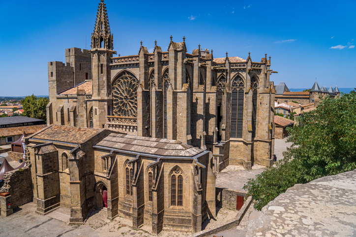 Eine große gotische Kirche in Carcassonne erhebt sich mit hohen Fenstern und verzierten Fassaden über die Altstadt.