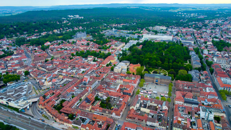 Luftaufnahme von Erlangen mit dicht bebauter Innenstadt, roten Ziegeldächern, großen Grünflächen und weitläufigen Wohnvierteln.