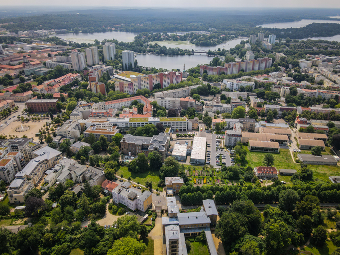 Luftaufnahme von Potsdam mit Wohnvierteln, zahlreichen Grünflächen, mehreren Seen und weitläufiger Stadtlandschaft.