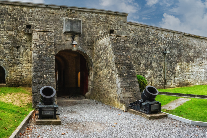 Steinernes Tor in einer historischen Festungsanlage in Dinant, flankiert von zwei alten Kanonen.