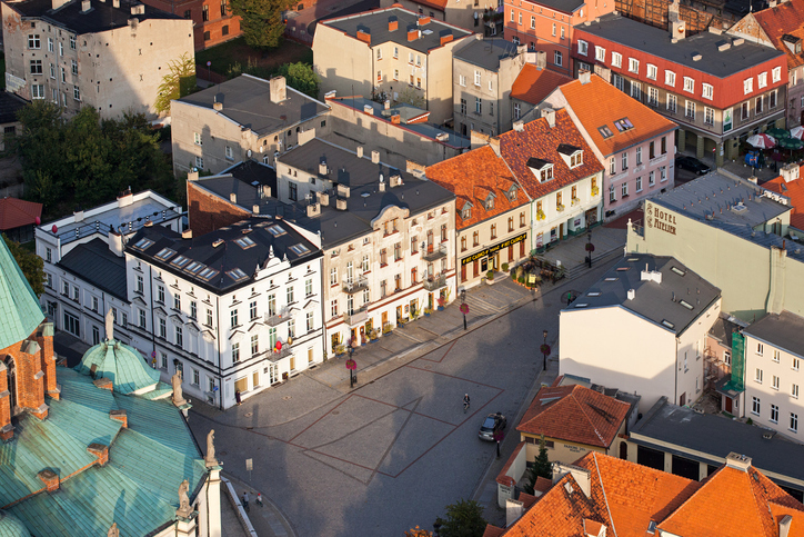 Luftaufnahme eines Platzes in Gniezno mit historischen Häusern, roten Dächern und offenen Flächen im Stadtzentrum.