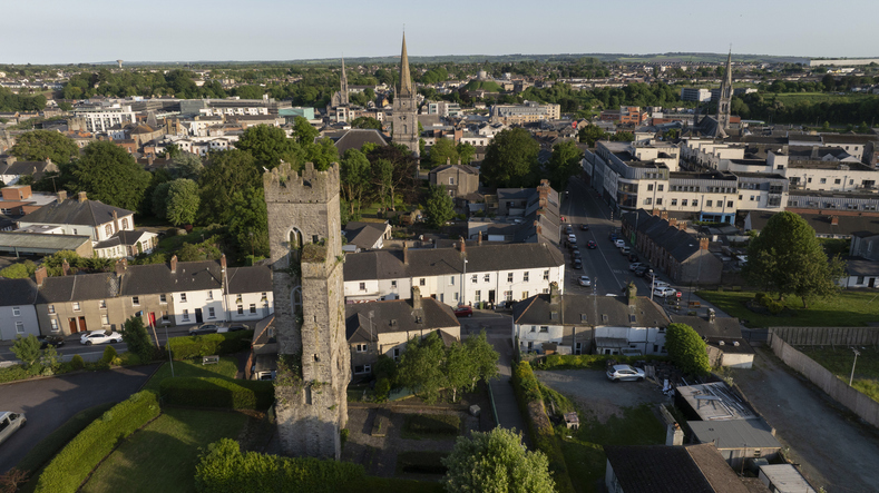 Luftaufnahme eines mittelalterlichen Steinturms in Drogheda, umgeben von Wohnhäusern, Gärten und dem Stadtzentrum.