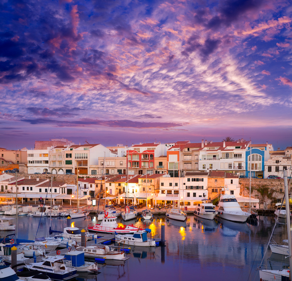 Boote im beleuchteten Hafen von Ciutadella bei Sonnenuntergang