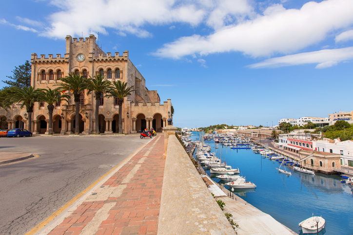 Historisches Gebäude am Rand des Hafens von Ciutadella mit Blick auf Boote und Wasser