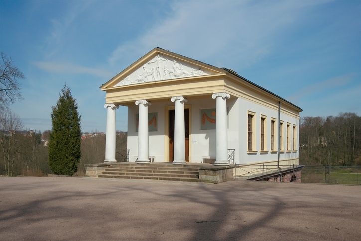 Ein weißes klassizistisches Gebäude mit Säulen steht frei auf einer Anhöhe in Weimar.