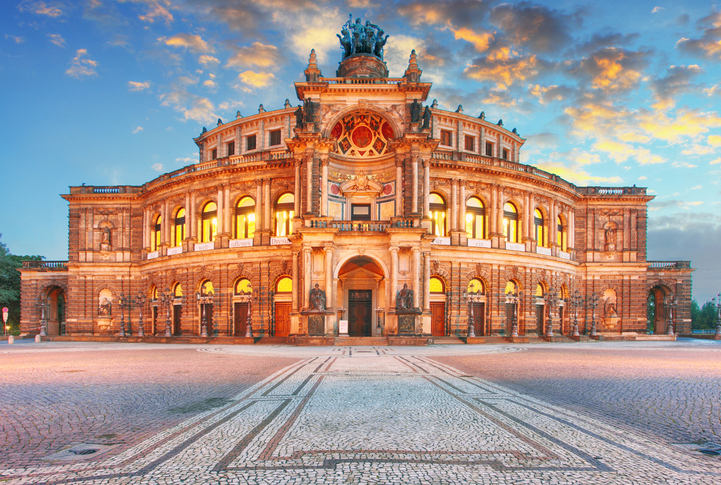 Beleuchtete Semperoper in Dresden am Theaterplatz mit prächtiger historischer Fassade und farbigem Abendhimmel.