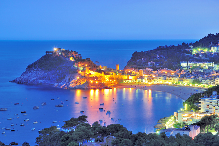 Beleuchtete Küstenstadt und Bucht bei Nacht an der Costa Brava nahe Lloret de Mar