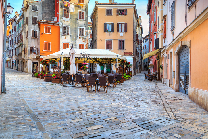 Kleine gepflasterte Gasse in Rovinj mit Straßencafé und farbenfrohen historischen Häusern