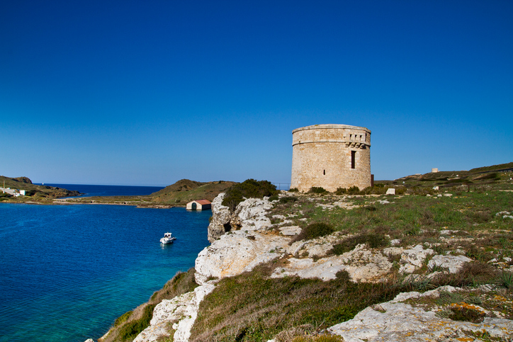 Alter steinerner Wachturm an einer felsigen Küste bei Ciutadella auf Menorca