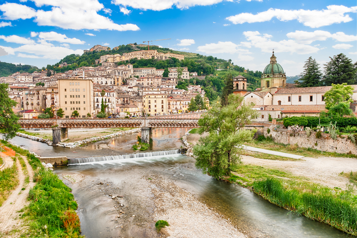 Weiter Blick über den Fluss, eine historische Eisenbrücke und die Altstadt von Cosenza mit Kirche und Burgberg