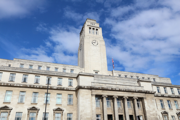 Parkinson Building der University of Leeds mit hellem Naturstein, markantem Uhrturm und klassischer Säulenfassade unter blauem Himmel.