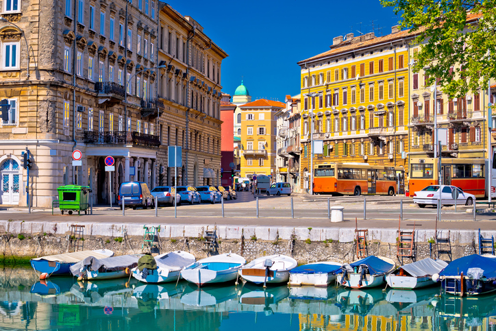 Kleine Boote im Wasser vor historischen Häusern und einer Straße in Rijeka