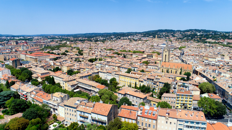 Ein weiter Blick von oben zeigt die Dächer von Aix-en-Provence und eine große Kirche inmitten der Stadt.